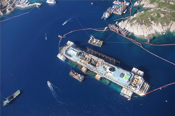 Giglio, 2014. július 20. Az olasz polgári védelem által 2014. július 20-án közreadott légi felvétel a 2012 januárjában zátonyra futott Costa Concordia olasz óceánjáró roncsáról az olaszországi Giglio-szigetnél hat nappal az után, hogy megkezdődött a hajótest vízfelszínre emelése. (MTI/EPA/Polgári védelem sajtóiroda)