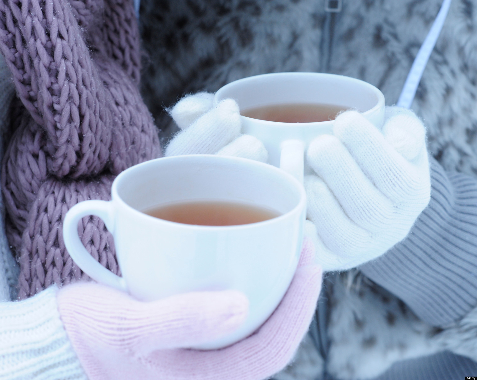 Close up of two young women holding hot tea on winter day
