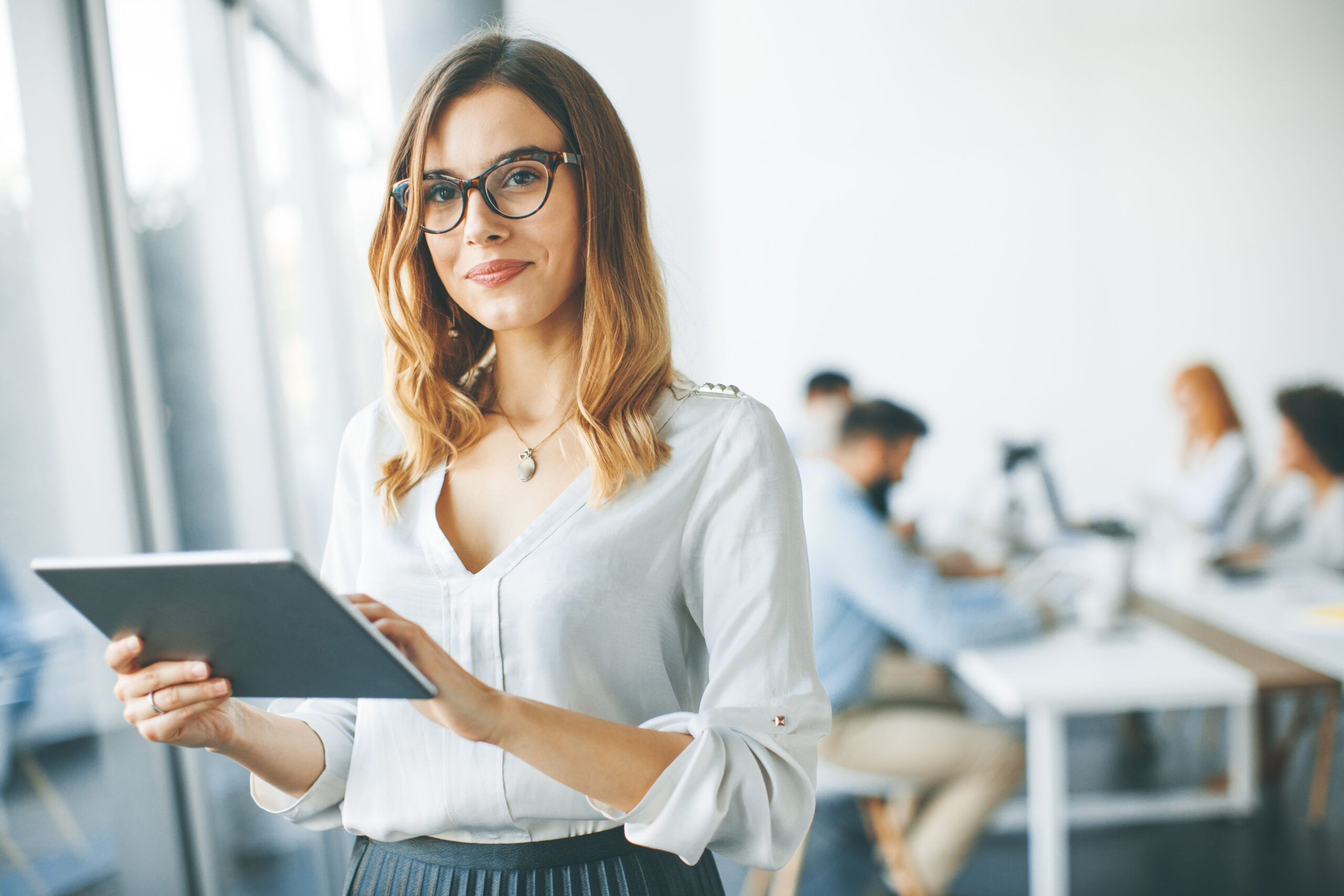 Elegant businesswoman standing in office with digital tablet