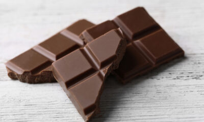 Black chocolate pieces on color wooden background