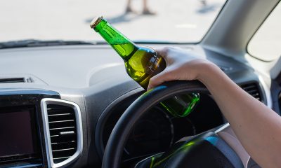 A Faceless Woman Is Drinking A Bottle Of Beer While Driving A Ca