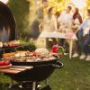 Group of friends having party outdoors. Focus on barbecue grill
