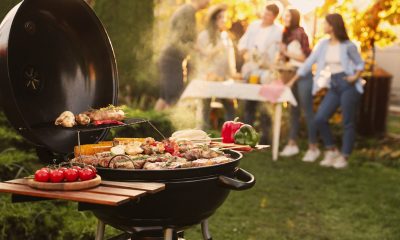 Group of friends having party outdoors. Focus on barbecue grill